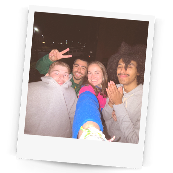 Polaroid-style photo of four friends posing together at night.